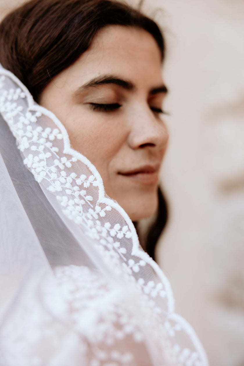 Woman wearing a white lace veil with a blurred background