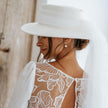 Bride in lace back wedding dress with wide-brim hat, elegant modern bridal style