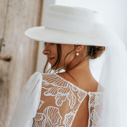 Bride in lace back wedding dress with wide-brim hat, elegant modern bridal style