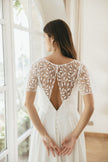 Bride wearing Ariette wedding dress with lace bodice, cap sleeves, and flowing skirt, styled for an elegant outdoor bridal look