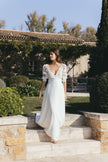 Romantic lace sleeve wedding dress with deep V neckline and flowing skirt, styled in a garden courtyard setting, Australia bridal fashion