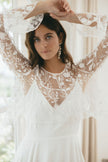Bride in sheer embroidered lace wedding dress with long sleeves and statement earrings, showcasing modern Australian bridal elegance and delicate details