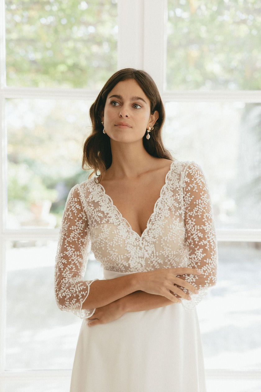 Bride wearing a sheer lace long sleeve wedding dress with deep V neckline, elegant Australian bridal style with delicate detailing